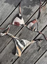 Conjunto de bikini azul con corpiño de triángulos movibles con almohadillas desmontables, que se ata al cuello y a la espalda. La bombacha es vedetina con tiritas a los costados para atar a medida de la cadera.