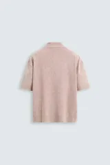 Polo de hombre color rosa, corte relaxed fit, tejido de punto con textura bouclé y mezcla de algodón. Tiene cuello solapa, cierre frontal con botones, manga corta y acabados en rib.