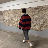 Buzo de manga larga con cuello polo blanco, a rayas horizontales color ladrillo y azul marino, con logo bordado en el pecho.