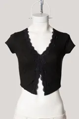 Remera corta negra de tejido acanalado, con escote en V y detalle de puntilla en el borde.