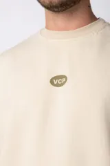 Buzo color beige de frisa con cuello redondo, mangas largas y logo bordado en el pecho.