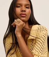 Anillo grande de metal con forma de flor alambrada y centro contrastante. Accesorio de bisutería con baño mixto.