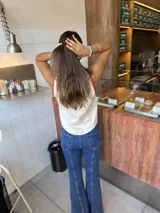 Pantalón de jean azul oscuro, de tiro alto y corte acampanado (flare), con costuras verticales marcadas en el frente y la espalda.