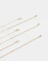 Set de tres collares cortos dorados. Uno con eslabones, otro con perlas y el tercero con dije de corazón alado y perla colgante.