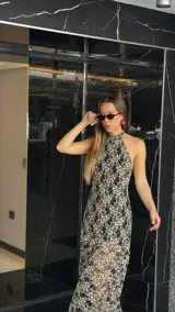 Vestido midi de encaje floral color beige sobre base negra, con cuello halter y falda con vuelo.