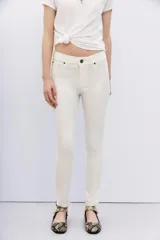 Pantalón jean blanco de tiro alto y calce skinny, con proceso de coating de acabado símil cuero. Pierna al cuerpo hasta el tobillo.