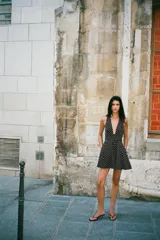 Vestido corto negro con lunares blancos, cuello halter y escote pico. Detalle de lazo en la espalda y cierre lateral con cremallera oculta.