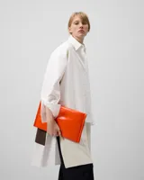 Camisa oversize blanca de manga larga con cuello solapa y botonadura frontal. Presenta una pieza superpuesta en la espalda que corresponde al delantero de un blazer.