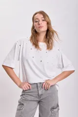 Remera blanca de corte holgado con mangas cortas y detalle de ojalillos metálicos en el frente.