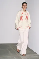 Sobrecamisa color crudo de Zara Woman Collection, con cuello solapa y manga larga. Tiene bolsillos de parche en el delantero y bordados combinados a contraste en color rojo. Cierre frontal con botones a presión ocultos.