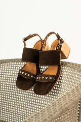 Sandalias de tacón de madera con tiras de gamuza marrón y detalles de tachas metálicas.