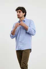 Camisa azul de corte clásico con botones y cuello, detalles de bolsillo en el pecho.