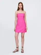 Vestido corto de lino color fucsia, con breteles finos y corte recto.