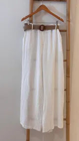 Pantalón blanco de lino, de corte ancho, con cintura elástica y cinturón de rafia extraíble.