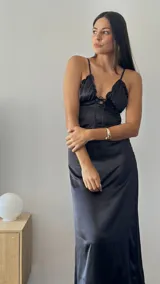Vestido midi negro de satén con breteles finos, escote en V con volados y lazo ajustable.