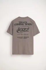 Remera gris de manga corta con cuello redondo y corte oversize. Estampa frontal con la palabra 'Jazz' y texto inferior.