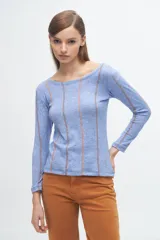 Remera gris de corte ajustado, con cuello redondo y mangas largas. Presenta líneas verticales bordadas en color verde claro y blanco.