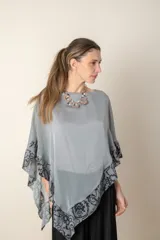 Blusa tipo poncho color gris con zócalo de tul bordado con motivos florales negros. Incluye una camiseta interior de spandex.