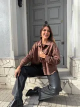Chaqueta marrón de gamuza con cuello camisero, cierre frontal con botones y bolsillos de parche en el pecho.