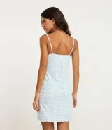 Conjunto de ropa de dormir compuesto por un camisón corto de tirantes ajustables con escote en V y detalle de encaje, y una bata de manga larga con el mismo estampado. Ambas prendas son de tejido viscolycra con estampado de cuadros vichy celestes y blancos.