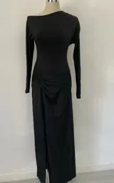 Vestido largo negro de mangas largas, con escote redondo y tajo lateral. Incluye cinturón de cuero negro con hebilla plateada y tachas.