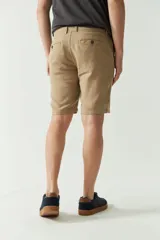 Bermuda de lino y algodón color beige, con bolsillos laterales y traseros, cierre con botón y presillas para cinturón.