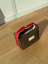 Neceser color beige de forma rectangular, con cierre superior y asa de mano.