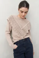 Sweater color beige de punto liso con detalle de crochet en el escote que cae en forma de pico sobre el pecho.