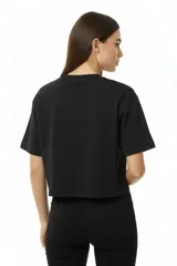 Remera de algodón negra, manga corta y cuello redondo, con un diseño abstracto de líneas curvas formadas por apliques de studs plateados en el pecho.