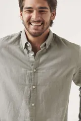 Camisa de lino color blanco, de corte regular, con cuello clásico y mangas largas.