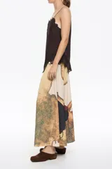 Falda midi de corte línea A con vuelo, confeccionada en poliéster. Presenta un estampado abstracto en tonos tierra, beige, marrón y verde musgo. Tiene cremallera lateral invisible y pliegues irregulares cosidos en la cintura.