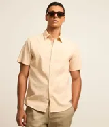 Camisa color beige claro de lino y algodón, corte comfort, manga corta, cuello camisero, cierre con botones y sin estampa.