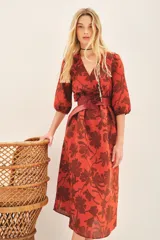 Vestido midi color ladrillo con estampado de flores marrones, escote en V, mangas 3/4 abullonadas y cinturón con aplique de flor.