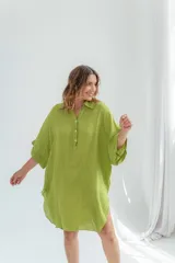 Vestido blanco de lino, corte holgado, con cuello camisero, mangas 3/4 y aberturas laterales.