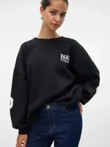 Sudadera negra de corte oversize con cuello redondo, hombros caídos y puños acanalados. Estampado frontal con la palabra "PARIS" en letras blancas y la frase "CITY OF DREAMS 1978" debajo.