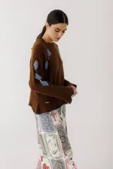 Sweater color gris claro con cuello redondo, mangas largas acampanadas y aberturas circulares en hombros y mangas con detalles de tela blanca.