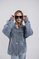 Campera de jean celeste con tachas plateadas, de corte recto, con cuello clásico, cierre frontal con botones metálicos, bolsillos con solapa en el pecho y bolsillos laterales.