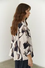 Camisa beige con estampado abstracto en tonos marrones y negros, cuello mao y mangas 3/4.