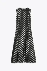 Vestido midi negro con estampado de lunares blancos, cuello redondo y sin mangas.