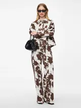 Chaqueta de jean con estampado animal print de vaca en tonos marrones y blancos, corte recto, cuello camisero y cierre frontal con botones.