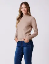 Buzo de punto color beige, con cuello alto y manga larga. Presenta detalles de costura en los hombros y puños acanalados.