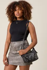 Bandolera color crema con correa fina regulable, cierre superior y herrajes metálicos plateados con forma de hebilla.