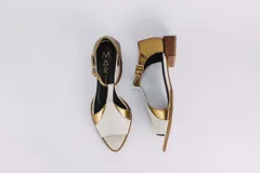 Sandalias de cuero color blanco con detalles dorados, taco bajo de madera y tira con hebilla al tobillo.