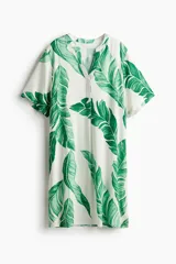 Vestido túnica corto de viscosa con estampado de hojas verdes, cuello mao con abertura en V, mangas cortas, corte holgado y tajos laterales.