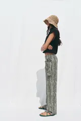 Pantalón de tiro alto con nudo delantero, de pernera ancha y estampado a rayas verticales en blanco y negro.