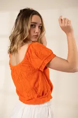 Top tejido de punto en color naranja, con diseño de patrones y mangas cortas, elaborado en 100% algodón.
