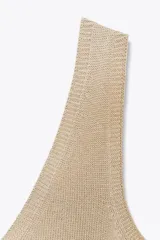 Top de punto color beige, con escote en pico y sisas anchas.