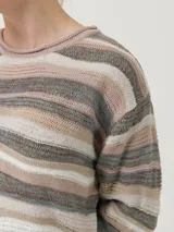 Sweater de punto con cuello redondo y mangas largas. Presenta un diseño de ondas horizontales en tonos beige, marrón y gris.