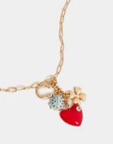 Collar dorado de tres hilos con dijes colgantes: corazón rojo con strass, trébol dorado, herradura dorada con logo de la marca y vaquita de San Antonio celeste con lunares blancos.
