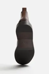 Bota Chelsea marrón de cuero, con elásticos laterales y tirador trasero. Suela negra con ligero tacón.